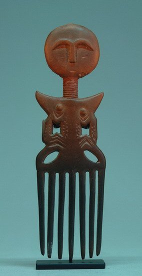 Peigne en bois, avec 7 longues dents . Le peigne est en forme de personnage, Le manche forme le buste et les dents une jupe.
