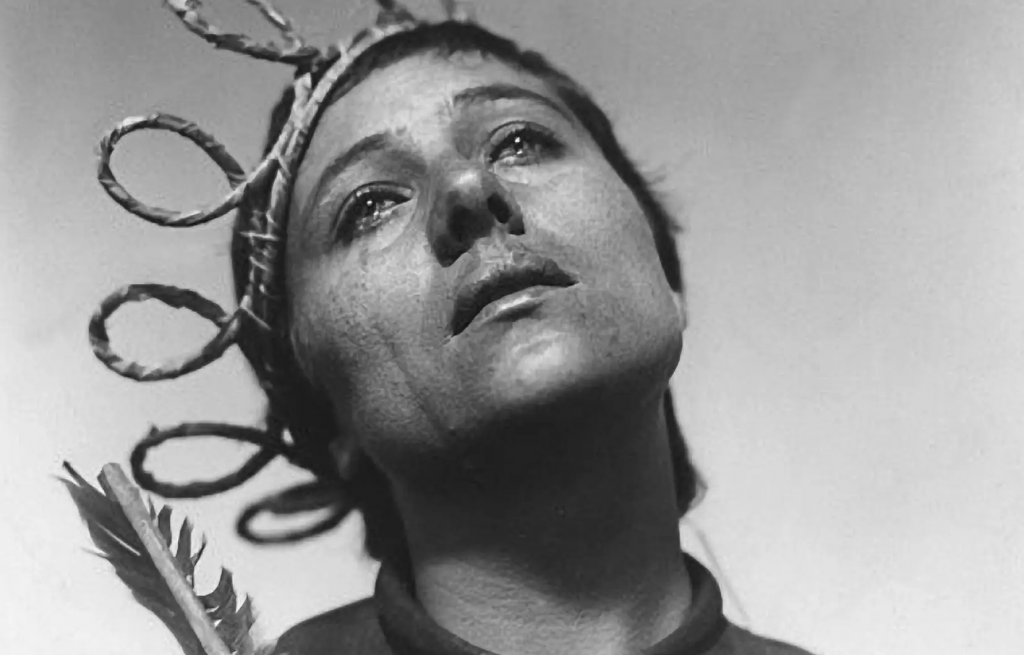 Jeanne d'Arc, une couronne de feuilles sur la tête, regarde vers le haut d'un air triste et pénétré.