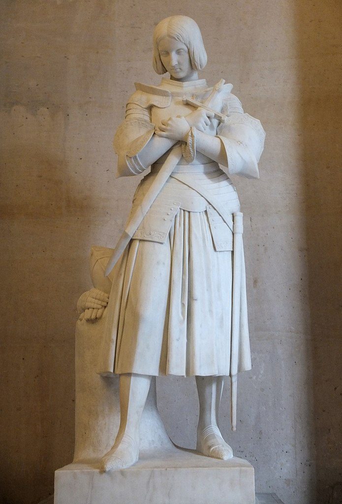 Statue en marbre de Jeanne d'Arc, en armure, tête penchée, serrant une épée contre son cœur.