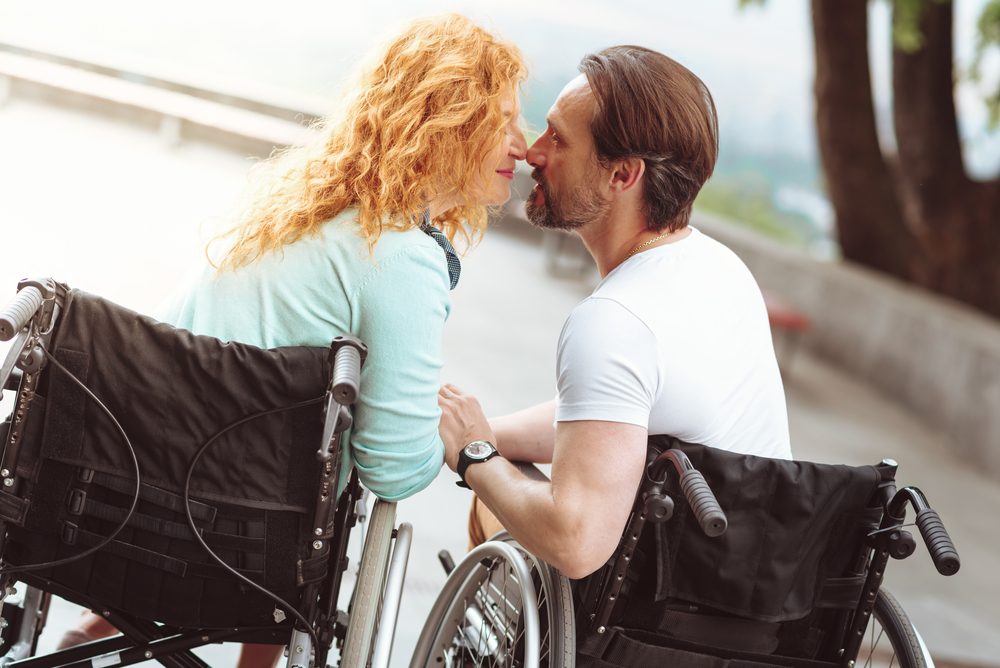 Deux personnes tenant leurs mains alors qu'elles sont assises dans des fauteuils roulants.