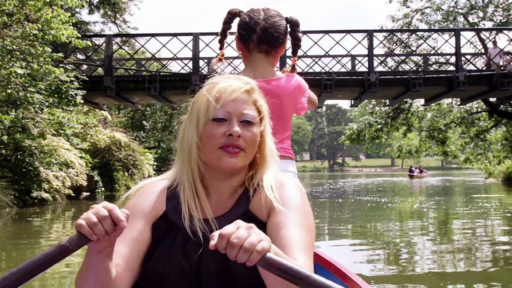 Sur un lac du bois de Vincennes, une femme rame dans une barque sur laquelle elle se trouve avec une petite fille