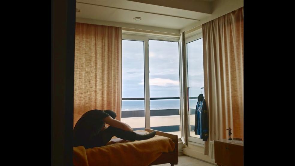 Un homme, vu de profil, recroquevillé sur son lit d'hôtel