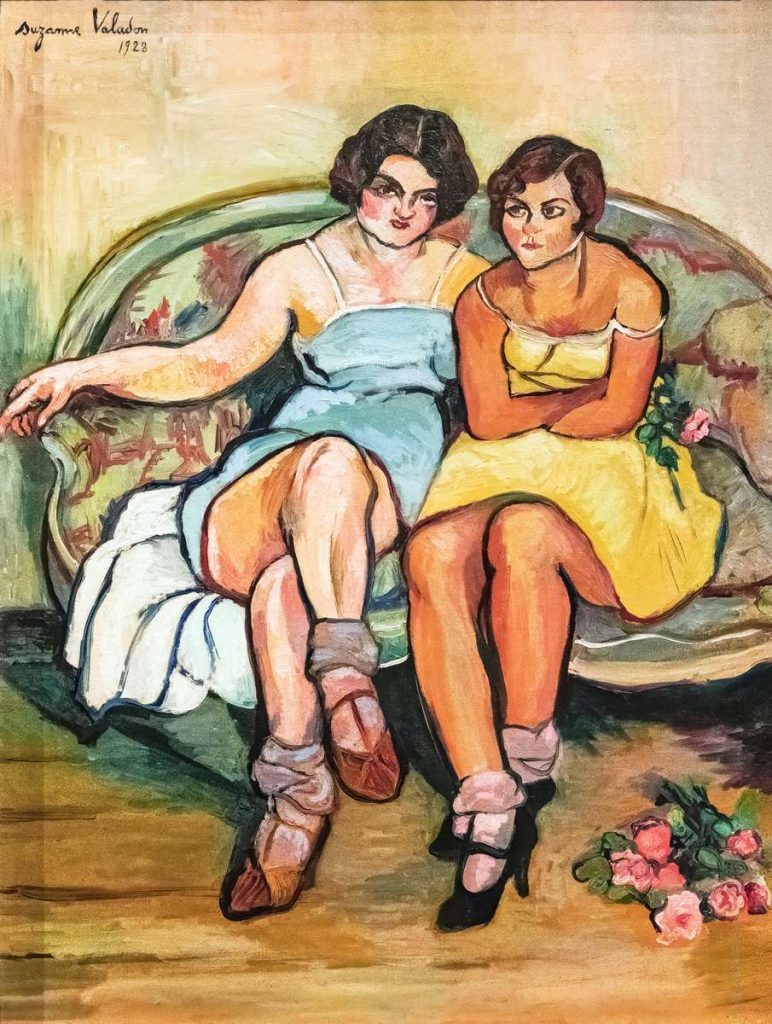 Deux femmes, ceveux courts, côte à côte sur un sofa, fixant le spectateur