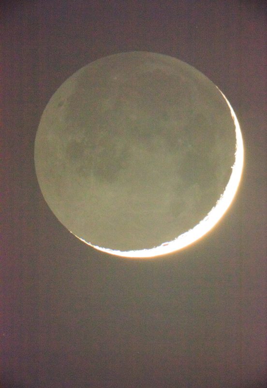 Moon in Earthlight de Wolfgang Tillmans, réalisée en 2015, capture un moment céleste fascinant : un croissant de Lune finement éclairé par la lumière directe du Soleil, tandis que le reste du disque lunaire est subtilement visible grâce à la lumière réfléchie de la Terre, appelée lumière cendrée. Le contraste saisissant entre la bande brillante, presque incandescente, du croissant et les détails plus diffus du reste de la Lune crée une ambiance mystérieuse et poétique. Les nuances douces de gris, de vert et de jaune traversent la surface lunaire, faisant ressortir ses reliefs et ses mers sombres. L’arrière-plan est plongé dans une obscurité profonde, renforçant l’impression d’apesanteur et d’immensité cosmique. Par cette œuvre, Tillmans unit une approche scientifique rigoureuse de l'observation astronomique à une sensibilité artistique rare, traduisant l’émotion brute de contempler notre satellite naturel."