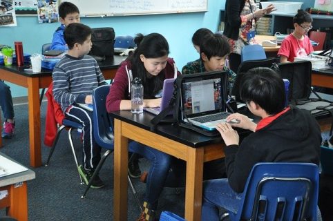 Photographie d'élèves dans une salle de classe avec des ordinateurs