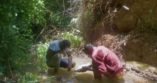 Deux hommes accroupis dans une rivière