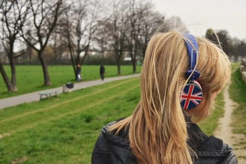 Une femme de dos dans la campagne, un casque audio sur les oreilles