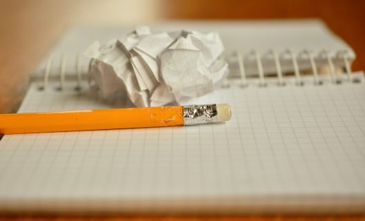 Un crayon sur un cahier, une feuille chiffonnée.