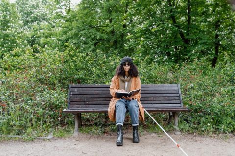 femme non-voyante dans un parc, avec un livre ouvert