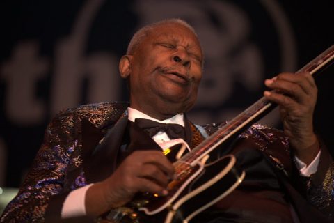 Le guitariste de blues B. B. King joue de la guitare les yeux fermés, en costume à paillettes.