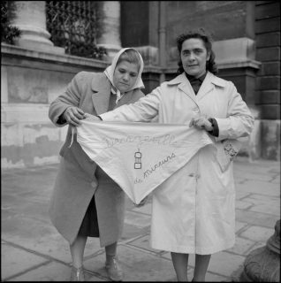 Deux femmes de mineurs de Decazeville en grève en janvier 1962. Elles déploient un foulard, orné de l'inscription « Decazeville femmes de mineurs ».