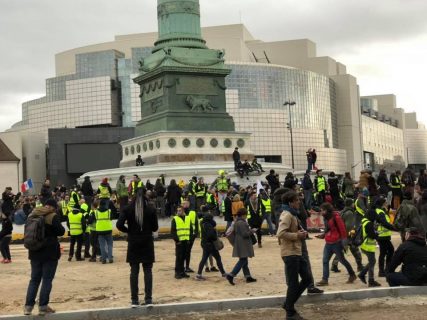 Plusieurs dizaines de personnes réunies sur la Place de la Bastille, certaines portant des Gilets Jaunes