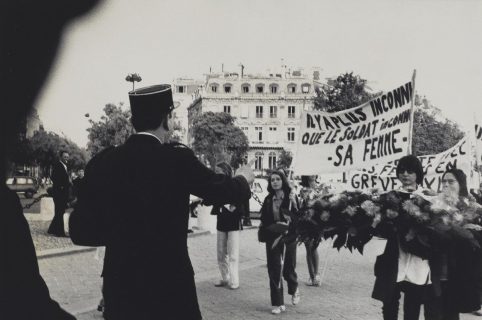 Un gendarme, de dos, fait face à des manifestantes tenant une banderole "Il y a plus inconnu que le soldat inconnu : sa femme"