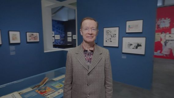 Paul Gravett au milieu de l'exposition Posy Simmonds.