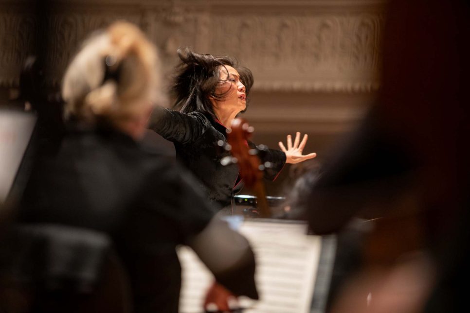 Photo capturant l'énergie de la cheffe d'orchestre dirigeant des musicien·nes